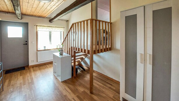 A room with wooden floors, a staircase with wooden railings, a radiator, a door, and a window with a curtain. - Awesome home in Eldsberga with kitchen (Eldsberga)