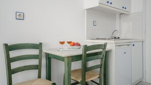 Eine kleine Küche mit weißen Schränken, einem Spülbecken und einem Essbereich mit zwei Stühlen und einem Tisch.