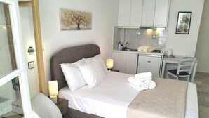 Ein Hotelzimmer mit einem Bett, einem Sessel, einem Schreibtisch und einer kleinen Küchenzeile.