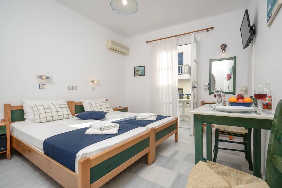 A bedroom with a bed, bedside tables, a desk with a chair, a mirror, and a window with curtains.