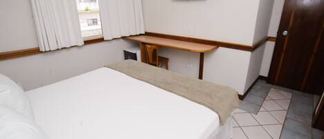 Una habitación de hotel con cama, escritorio, televisor y puerta.