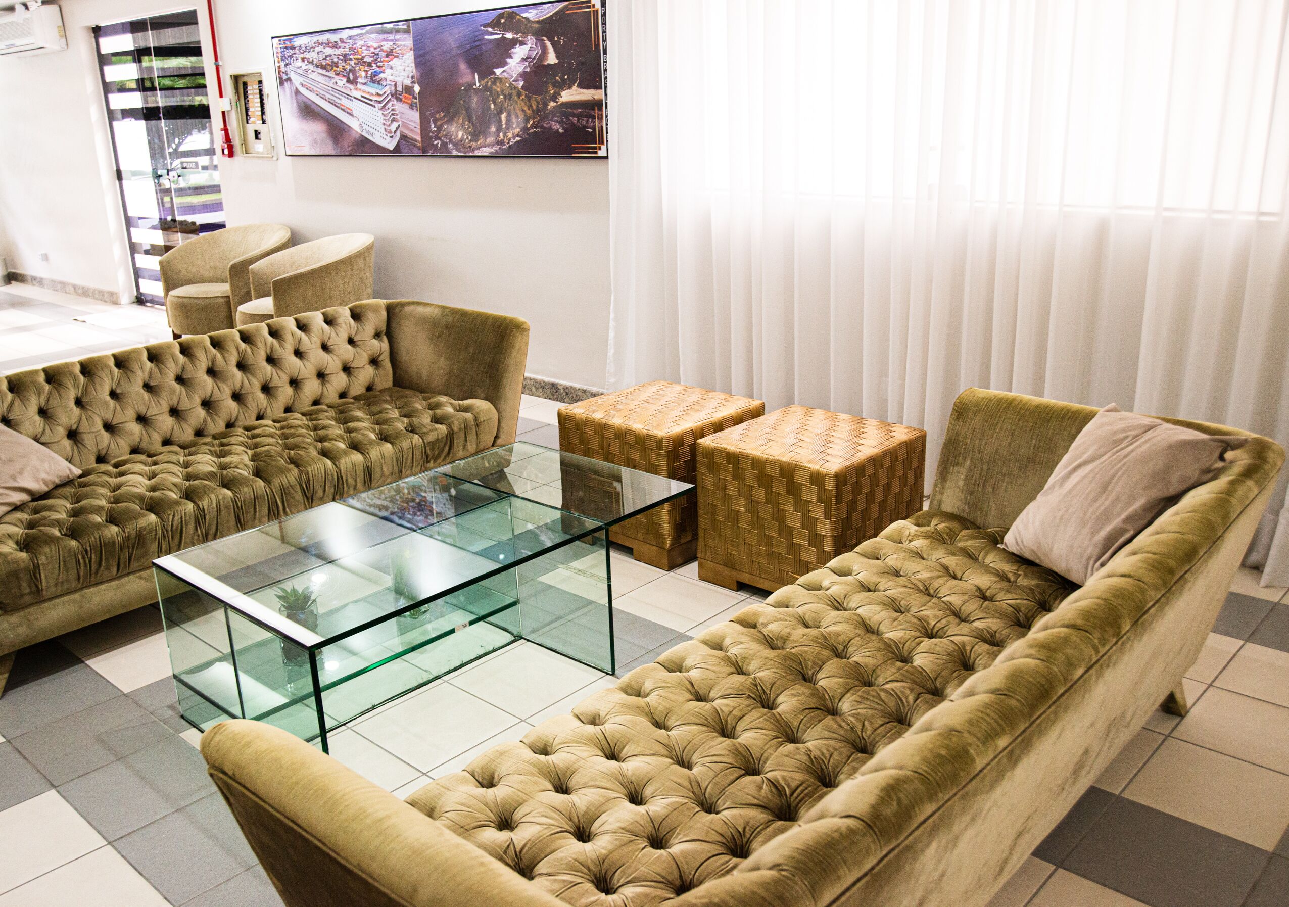 A living room with a sofa, armchairs, a glass coffee table, and a television mounted on the wall.