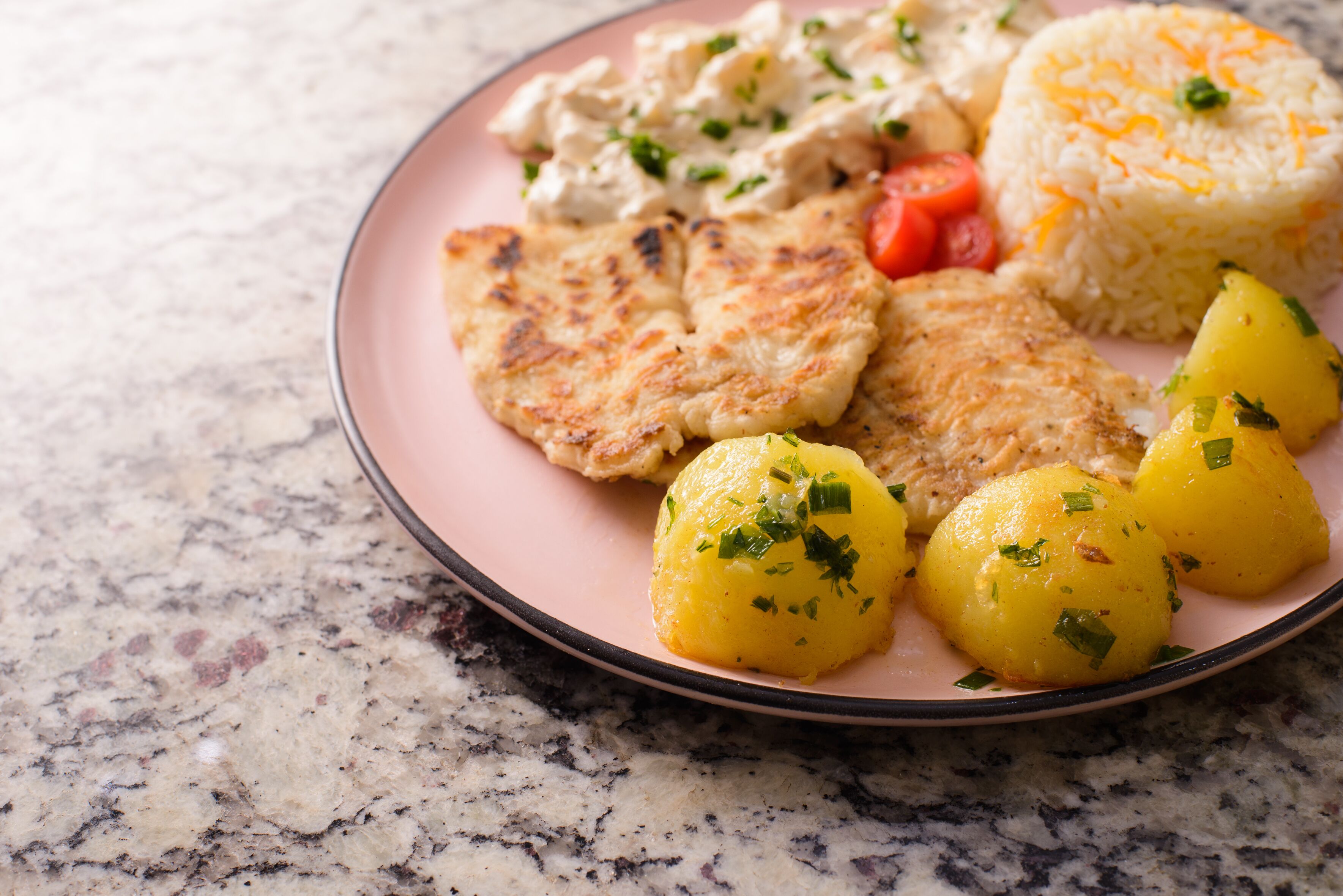 A plate with grilled chicken, boiled potatoes, rice, and a side salad.