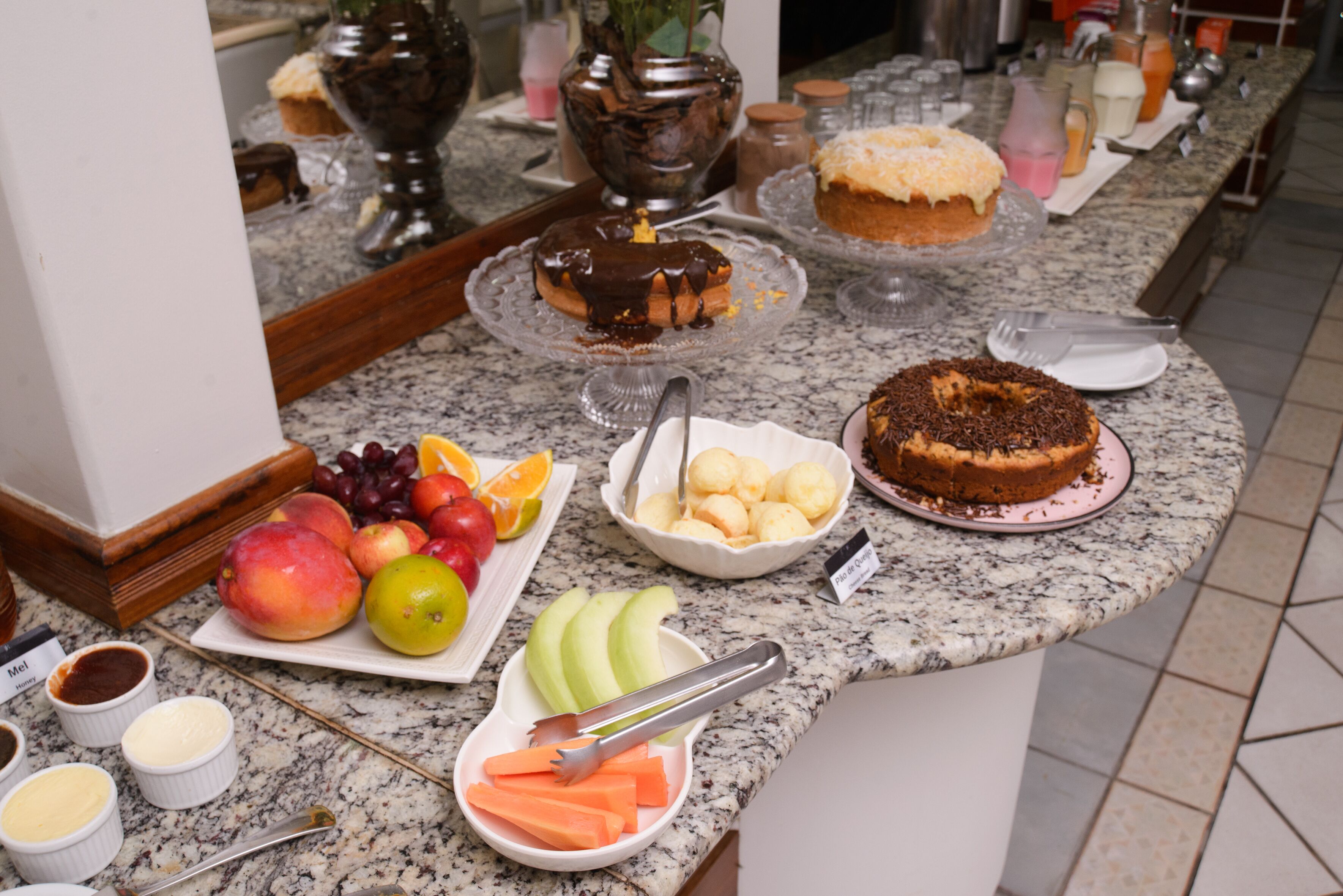 A buffet table with various food items including fruits, pastries, and a cake.