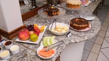 A buffet table with various food items including fruits, pastries, and a cake.