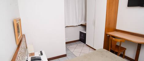 Ein Schlafzimmer mit einem Bett, einem Nachttisch, einer Lampe und einem Holztisch mit Stuhl.