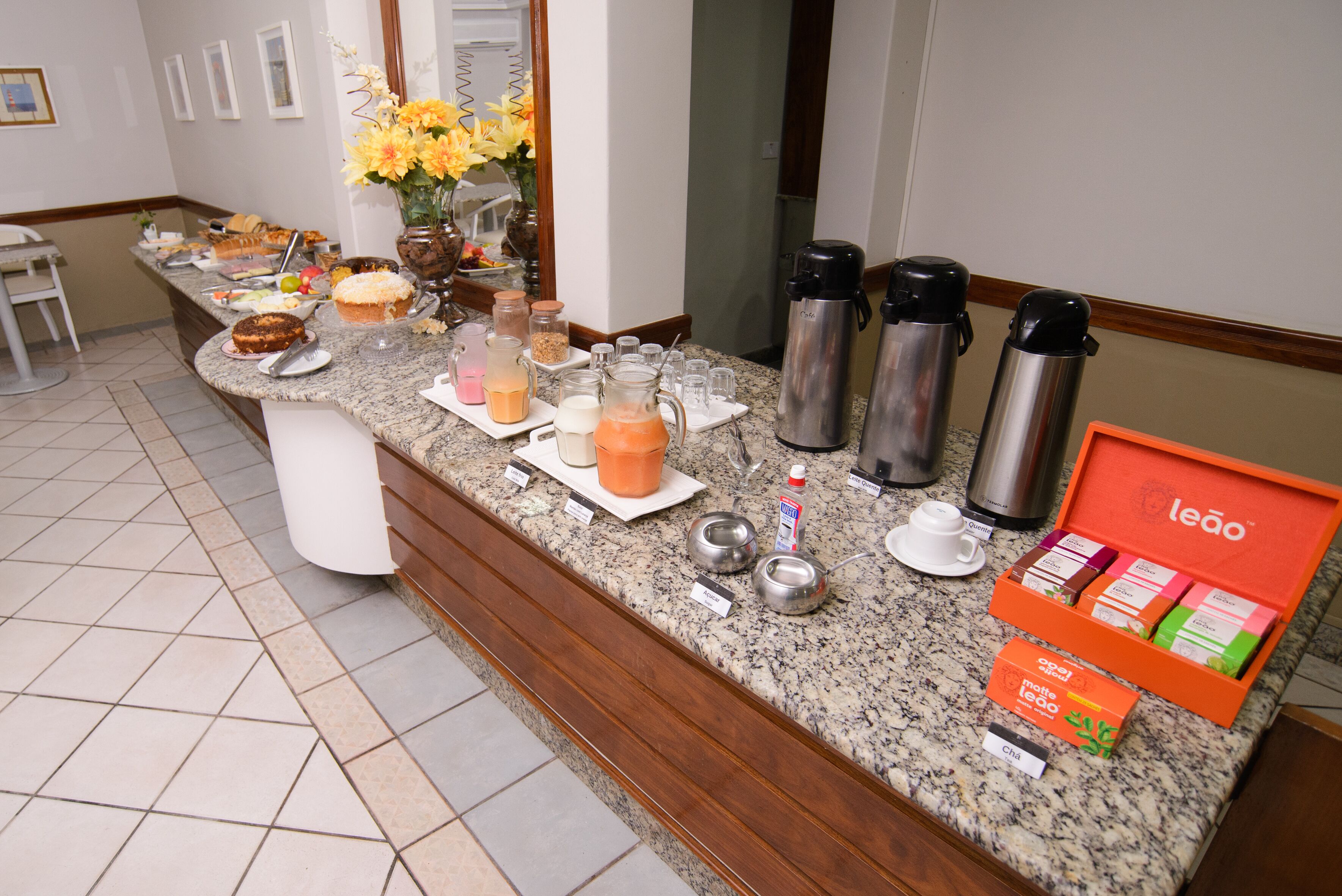 A breakfast buffet with various food items, coffee makers, and a box of Leao coffee.