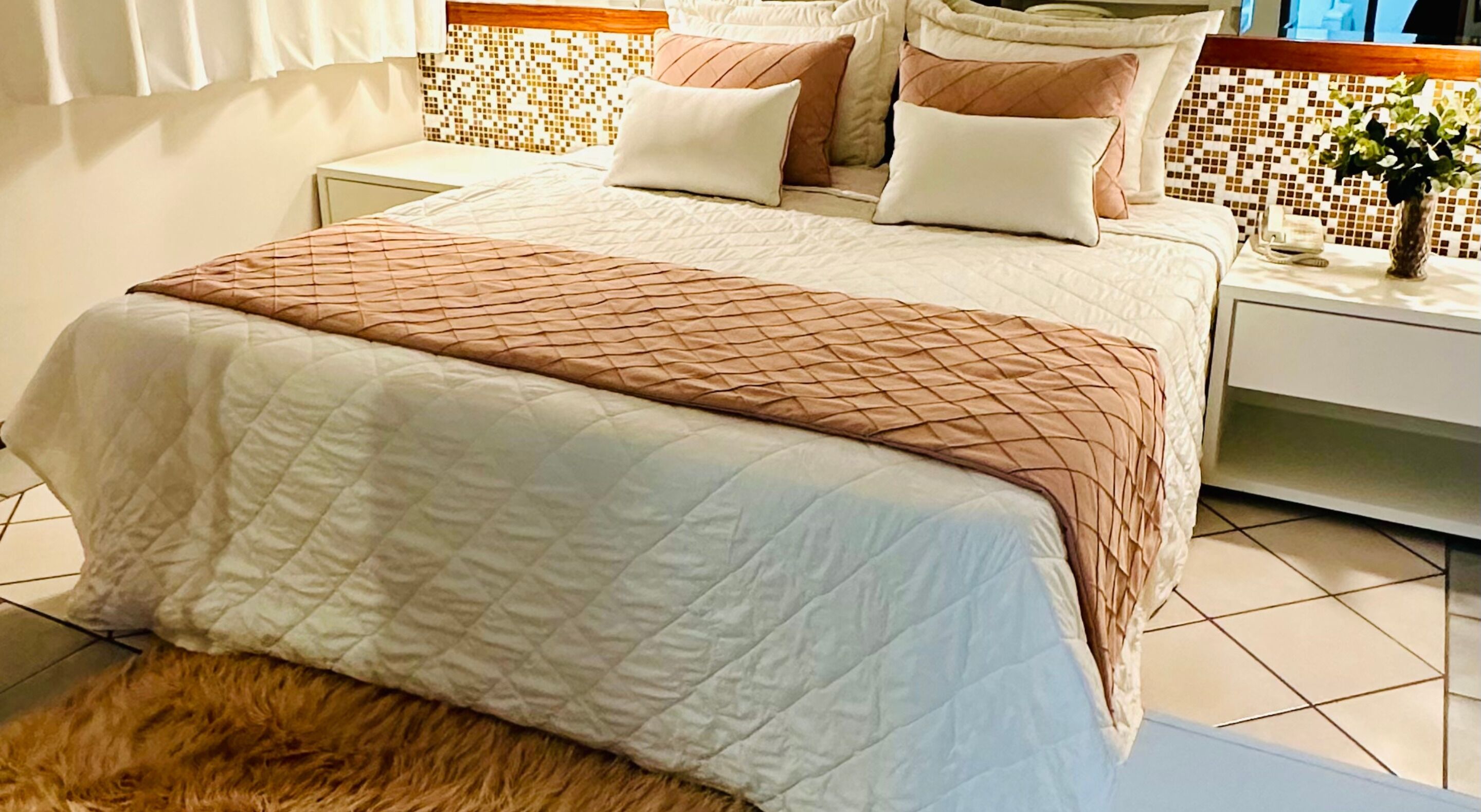 A neatly made bed with a quilted cover and a decorative throw blanket.