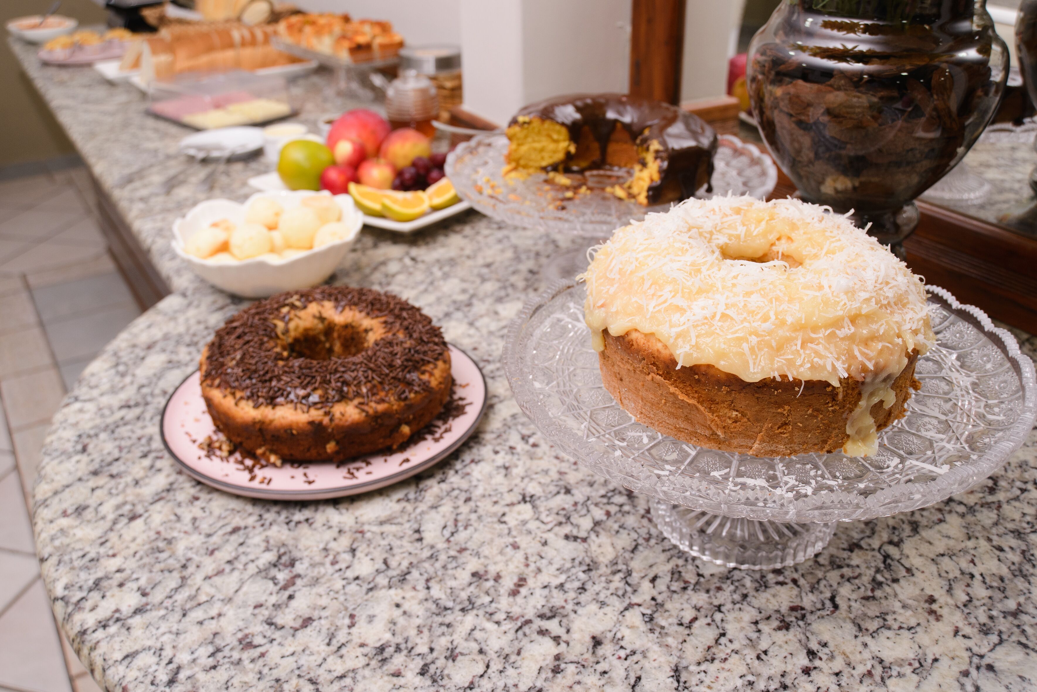 A kitchen counter with various baked goods, including a chocolate cake and a coconut-topped cake.