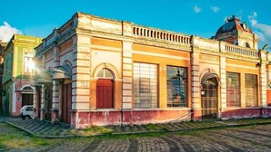 Un edificio histórico con una imponente torre de reloj, ventanas arqueadas y una puerta roja.