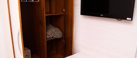 Ein Zimmer mit einem Holzschrank, einem flachbildfernseher an der Wand und einer kleinen weißen Kommode mit einem Logo.