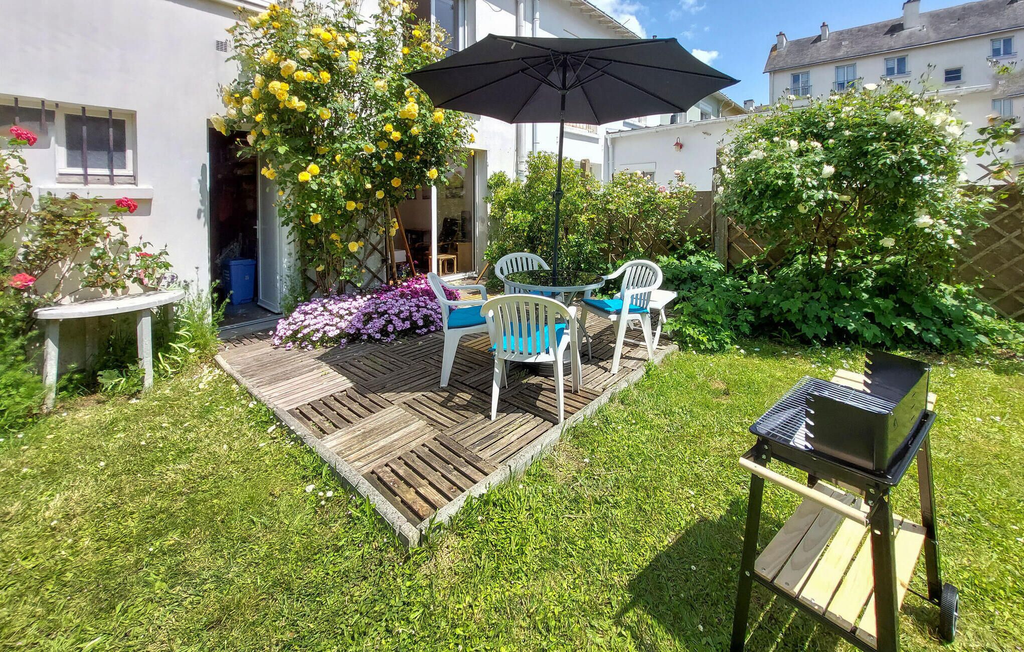 A patio with a wooden deck, outdoor seating, and a grill.