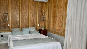 Une chambre avec un mur en bois, un lit avec une literie blanche et une table de chevet avec une lampe.