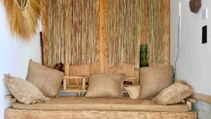 Un canapé en bois rustique agrémenté de coussins tissés, une table basse en osier et un panier en osier.