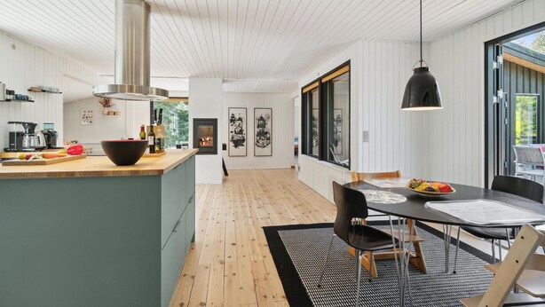 Una cocina moderna con una isla central, un comedor con mesa y sillas, y un ventanal que proporciona luz natural.