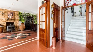 Un hall d’entrée spacieux avec une cheminée, un escalier et un mur décoratif.