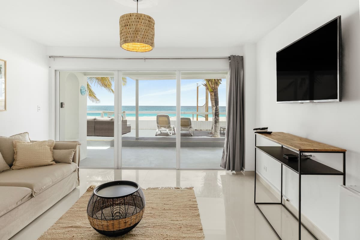 A modern living room with a sofa, a coffee table, and a TV mounted on the wall.