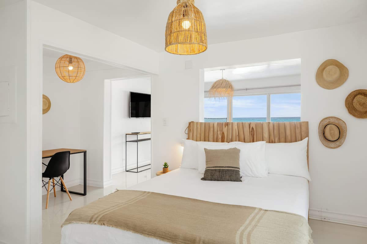 A modern bedroom with a large bed, a desk, and a TV.