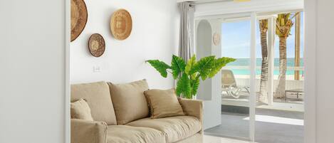 A modern living room with a beige sofa, a wooden coffee table, and a large plant.