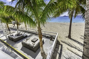 A beachside area with outdoor seating and palm trees. - Cocovaa (Simpson Bay)