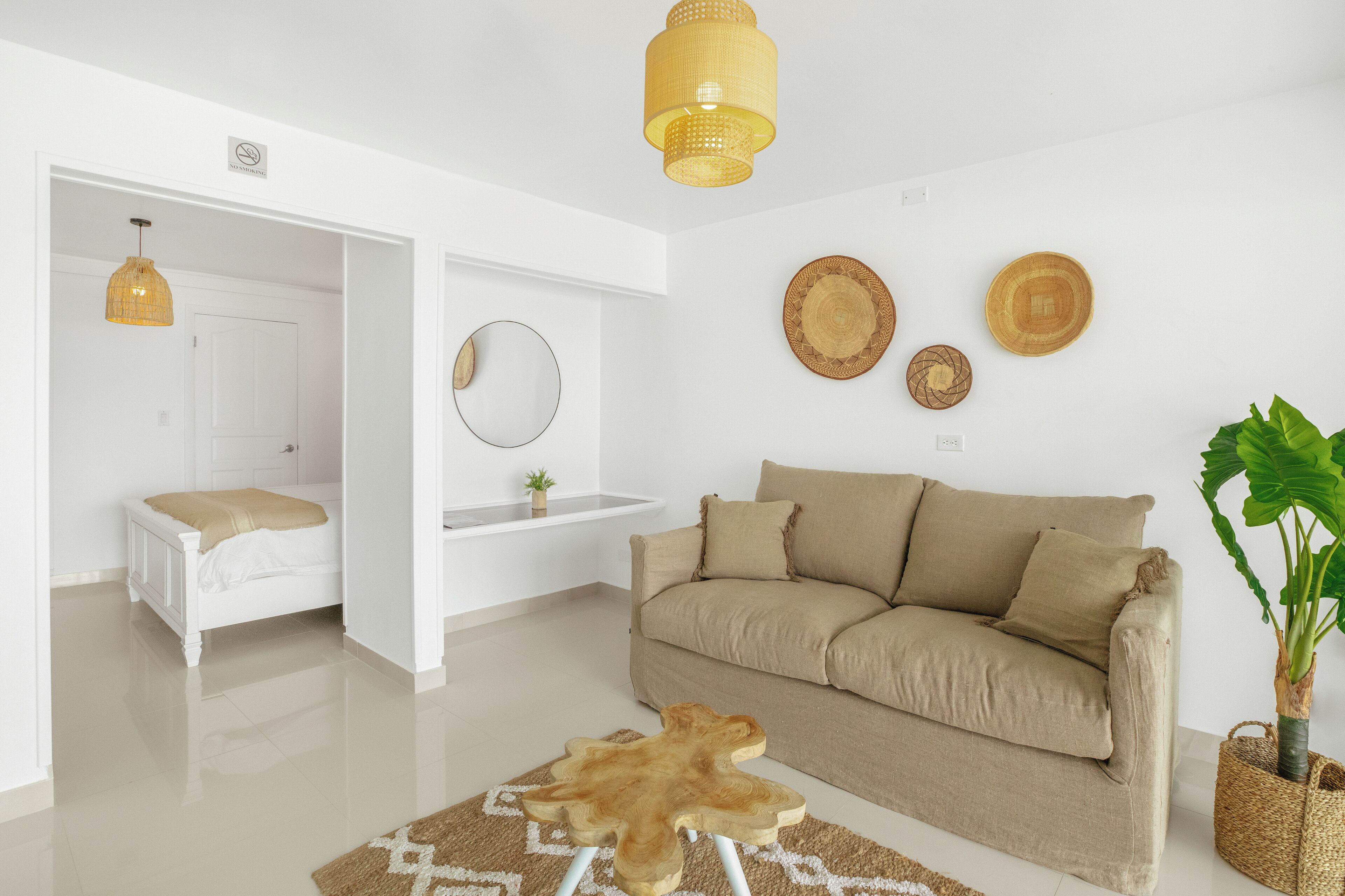 Un salon moderne avec un canapé beige, une table basse en bois et une grande plante en pot.