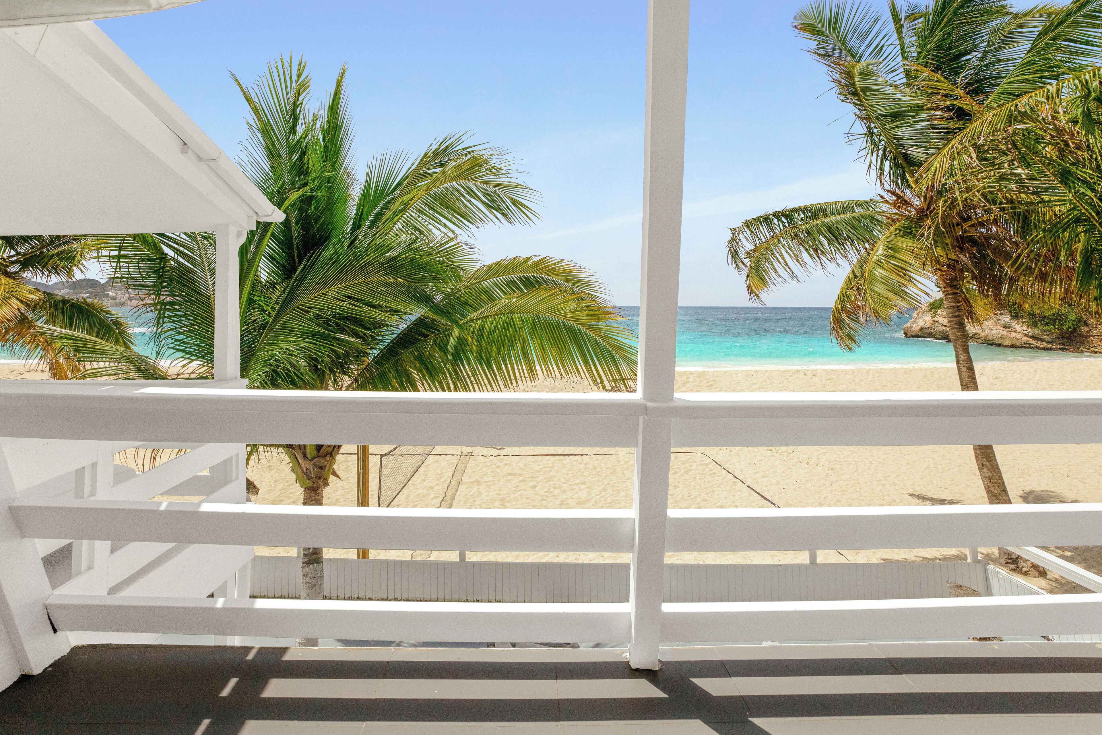 Un balcon avec vue sur une plage et des palmiers.