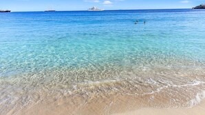 A clear beach with calm waters, a sandy shore, and a distant cruise ship. - Cocovaa (Simpson Bay)
