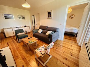 Un espace de vie compact comprenant un canapé, une petite table, une chaise et un lit.