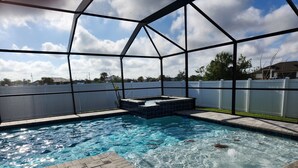 A swimming pool with a clear blue water, surrounded by a white fence and a covered area with a metal frame. - Cape Coral Pool/Spa Home (Cape Coral)