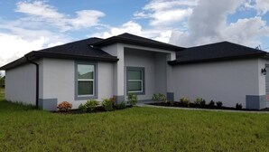 A modern two-story house with a flat roof, large windows, and a well-maintained lawn. - Cape Coral Pool/Spa Home (Cape Coral)