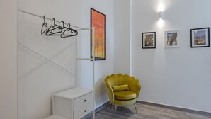 Une pièce avec une armoire blanche, une chaise jaune et trois tableaux encadrés accrochés au mur.