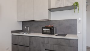 Une cuisine moderne dotée d’un four à micro-ondes encastré, d’un évier et de meubles de rangement gris.