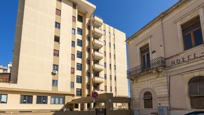 A tall beige building with multiple balconies and a sign indicating a hotel.