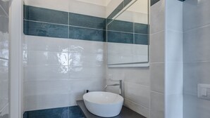 A bathroom with a white sink, dark blue tiles, and a mirror.