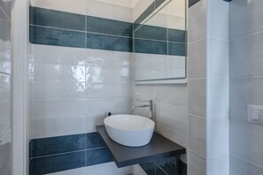A bathroom with a white sink, dark blue tiles, and a mirror. - Comfortable apartment with little balcony, furnished with taste and perfect for two people. The accommodation is located in a very convenient position: outside the ZTL but at the same time a few steps from the historic centre, reachable on foot in five m (Lecce)