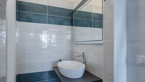 A bathroom with a white sink, dark blue tiles, and a mirror.