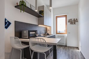 A modern kitchen with a built-in microwave, two white chairs, and a window with a view. - Comfortable apartment with little balcony, furnished with taste and perfect for two people. The accommodation is located in a very convenient position: outside the ZTL but at the same time a few steps from the historic centre, reachable on foot in five m (Lecce)