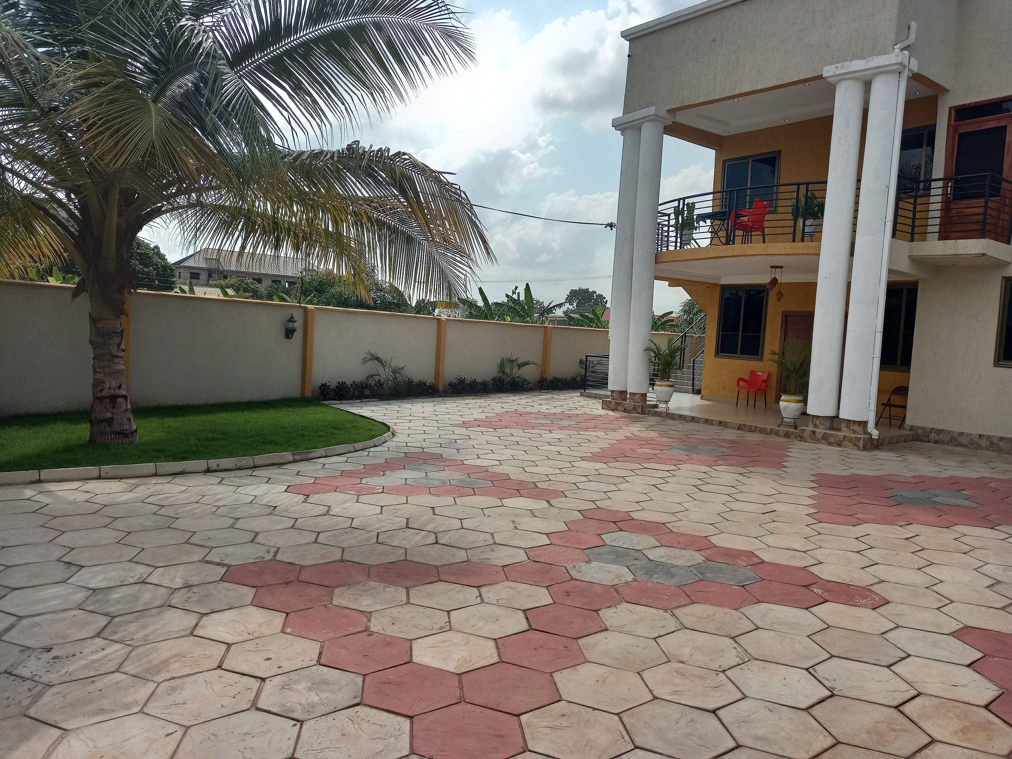 A residential building with a balcony, a palm tree, and a hexagonal tile floor.