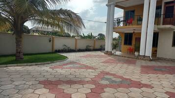 A residential building with a balcony, a palm tree, and a hexagonal tile floor.