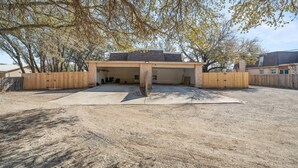 A covered parking area with a gravel surface, surrounded by a wooden fence and trees. - The Lake Escape @Brownwood (Brownwood)