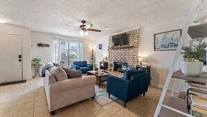 A living room with a fireplace, a ceiling fan, and a TV mounted on the wall. - The Lake Escape @Brownwood (Brownwood)