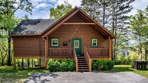 A wooden cabin with a porch, a staircase, and a door marked '022'. - Family Retreat - HotTub! Theater! FirePit! Wifi! Grill! Jacuzzi in both bedrooms (Pigeon Forge)