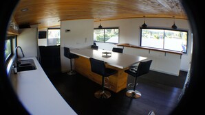 A modern kitchen with a central island, bar stools, and a large window providing a view of the outdoors.