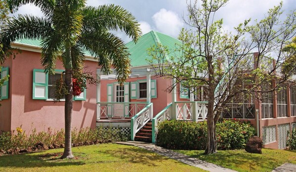 A building with a pink facade, green shutters, and a white staircase leading to a porch. - 5 bedroom Villa with pool, walk to the beach (St Thomas Parish)
