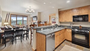 A kitchen with wooden cabinets, a built-in stove, and a dining area with a table and chairs. - Freshly updated 3 bedroom ski in and out Morning Eagle condo (Whitefish)