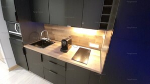 A modern kitchen with a sink, coffee maker, and a built-in oven. - Studio Sensuel (LE CAP D'AGDE)