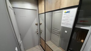 A hallway with a door, a cabinet with a sign, and a wooden panel. - Studio Sensuel (LE CAP D'AGDE)