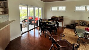 A spacious living room with a dining area, a ceiling fan, and a view through large sliding glass doors to an outdoor patio. - Beautiful, centrally located, short drive to beaches and stores. (George Town)