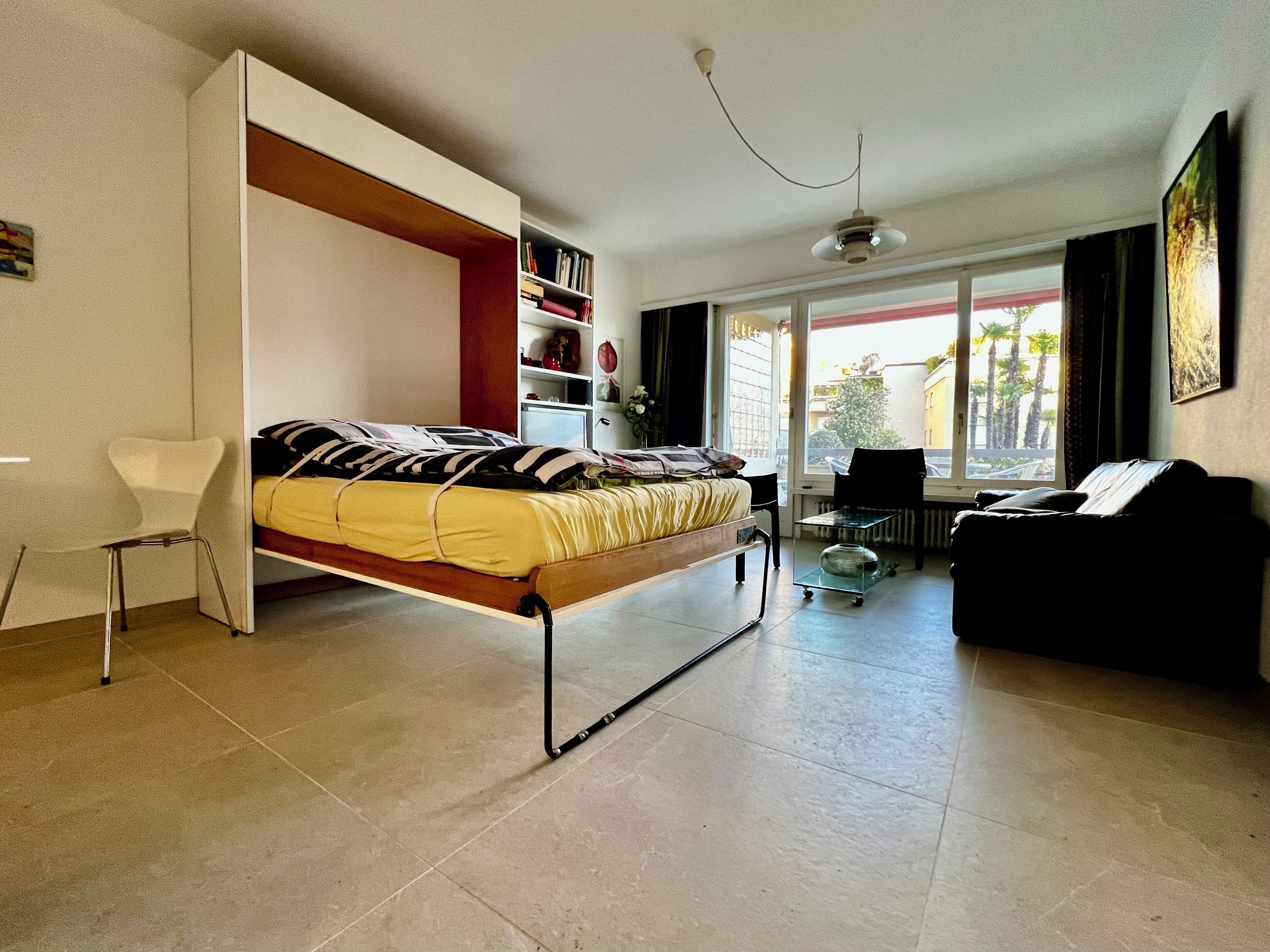 Une chambre à coucher moderne avec un lit, une chaise, un canapé et une bibliothèque.