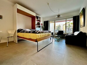 Un dormitorio moderno con cama, una silla, un sofá y una estantería.